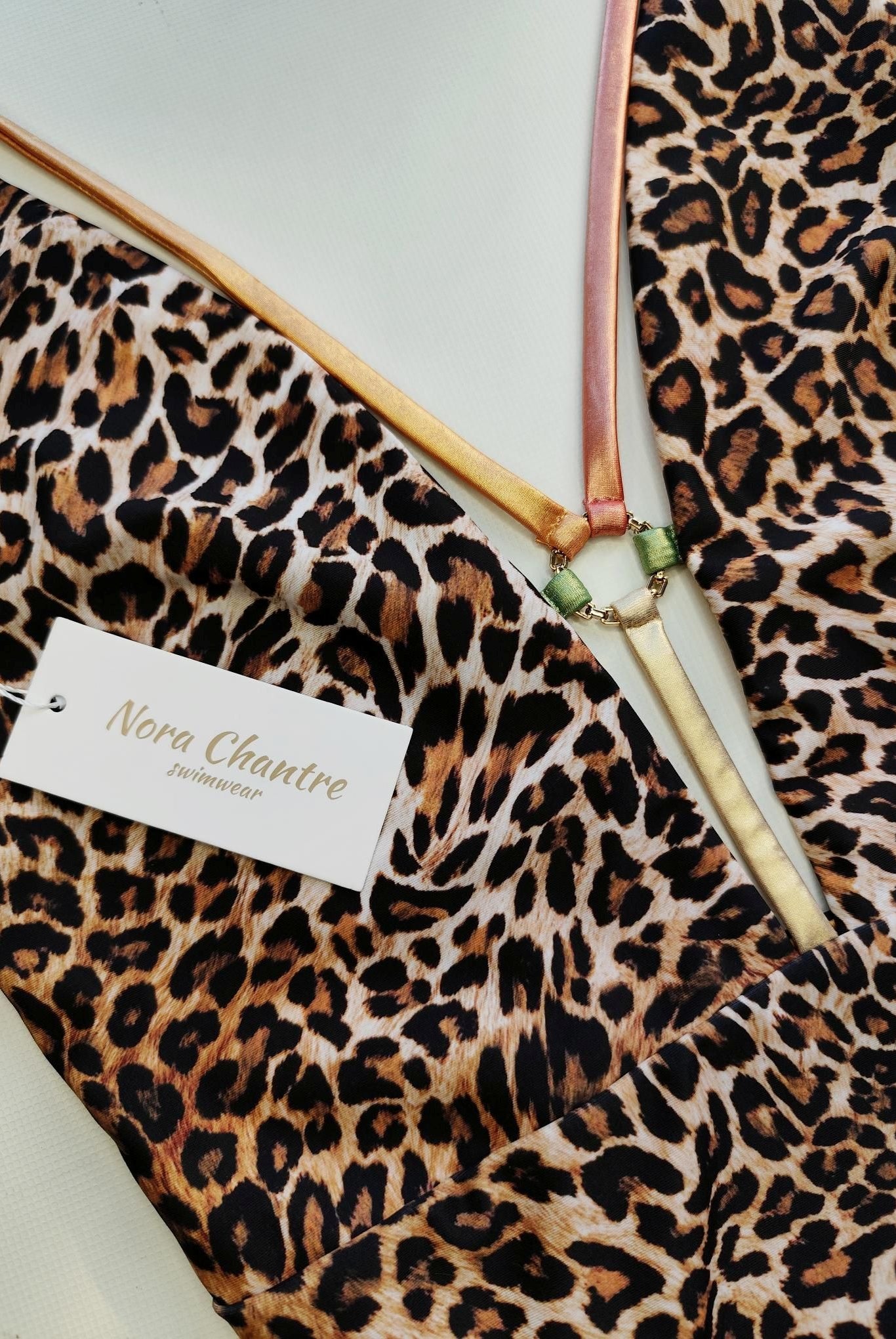 Leopard print swimsuit detail with gold ring accessory and metallic straps