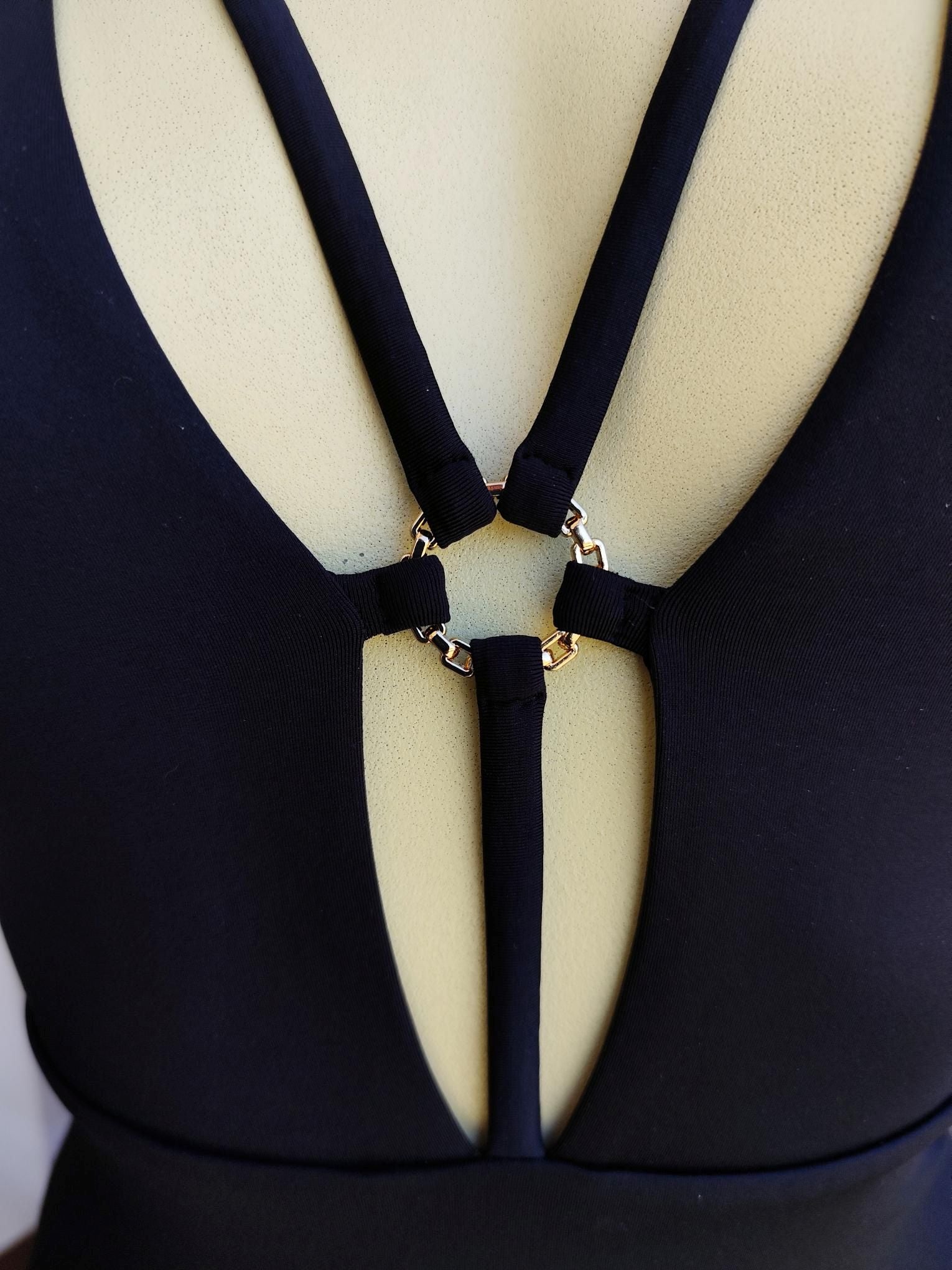 Black swimsuit detail with gold ring accessory and deep V neckline