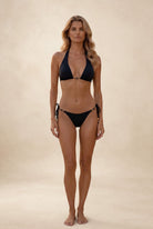 Front view of black triangle bikini with gold infinity connector and tie side bottoms on neutral studio background