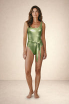 Bañador Lumière verde claro metalizado con escote redondo y cinturón anudado en la cintura, vista frontal en fondo beige