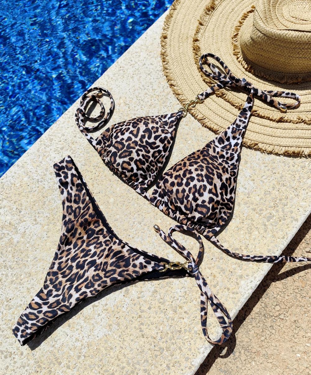Bikini Seraya estampado leopardo con detalle dorado, sobre piedra junto a piscina